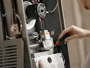 Furnace repair technician inspecting internal components and wiring in Virginia Beach, VA