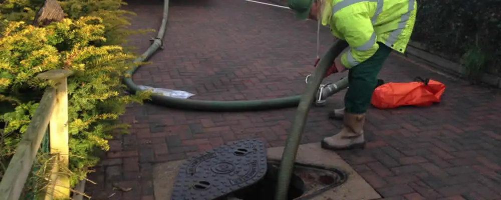 Septic tank cleaning technician servicing a septic tank with a vacuum hose in Virginia Beach, VA