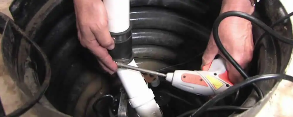 Sump pump installation technician connecting PVC discharge piping in Virginia Beach, VA